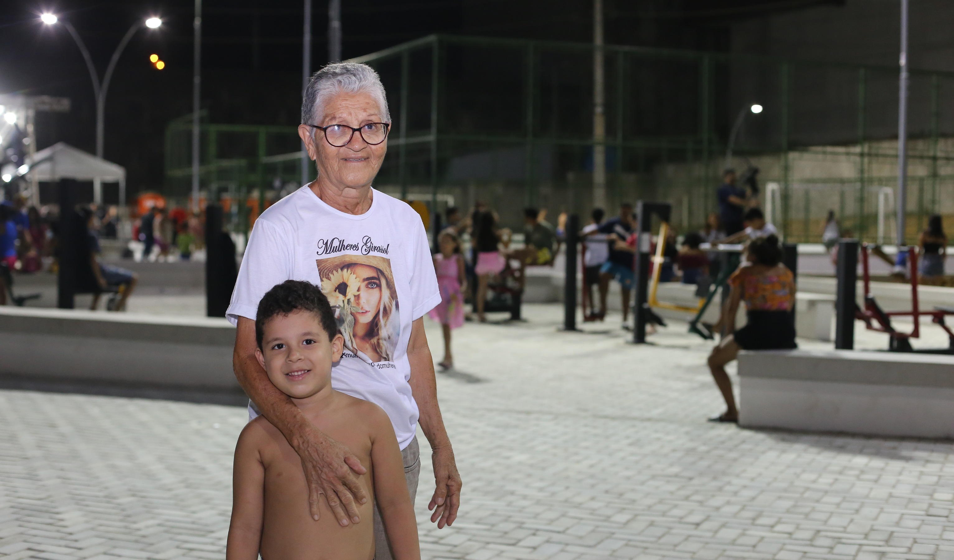 senhora posa para a foto com o neto ao lado